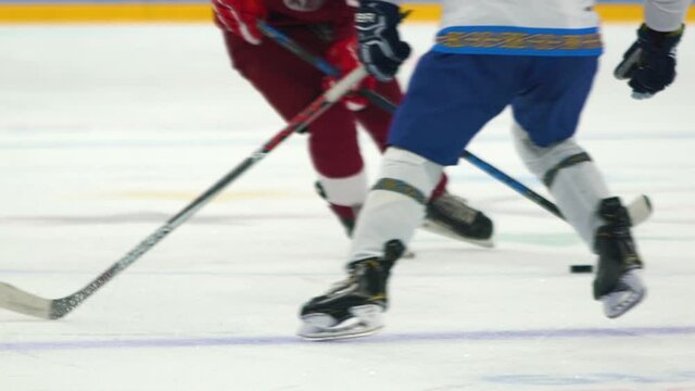 Hockey. Olympic sport. Hockey player in attack. Active actions of a hockey player. Powerful braking of hockey skates on ice close-up. Puck on the stick.