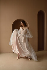 Fototapeta premium Portrait of a young beautiful bride in full growth. Girl posing in a room near the window.