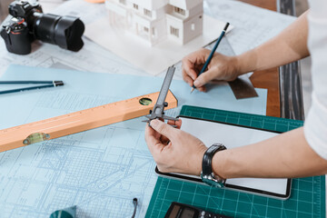 Engineering hands hold vernier caliper working and checking drawing blue print scale on workplace.  Architecture, engineering, business and civil concept.