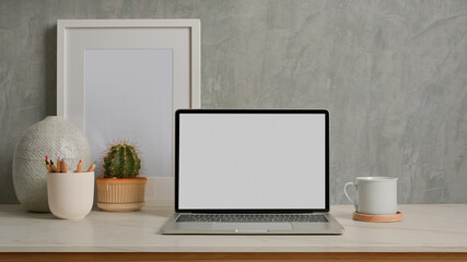 Close up view of home office desk with laptop, mock up frame and decorations