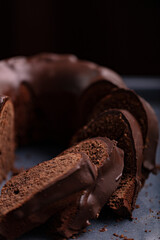Dark chocolate cake covered with icing covered on a dark background. Selective focus.