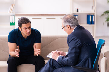 Obraz premium Young man visiting old male psychologist