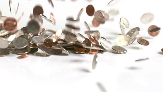 US coins falling onto a white surface in slow motion