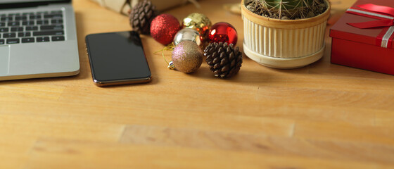 Wooden desk with smartphone, laptop and decorations in office room