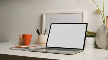 Cropped shot of worktable with laptop, supplies and decorations in home office room