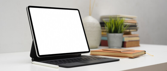 Side view of workspace with tablet, accessories, books and decorations in home office room