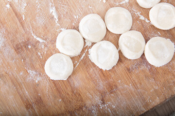 Round cake-shaped white noodles used to roll dumpling wrappers on a cutting board