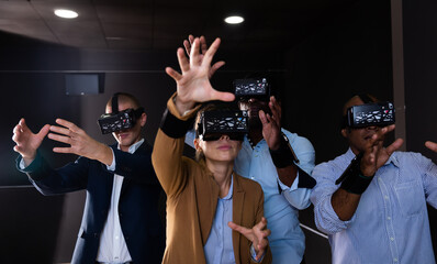 Portrait of group of young adult people with virtual reality goggles gesturing standing in dark room
