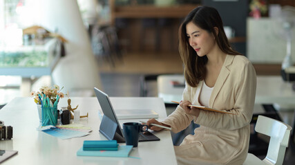 Businesswoman working with tablet and schedule book in modern office room