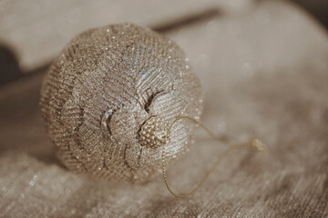 Close-up of beautiful beige Christmas ball on a beige glittering background. Selective focus , blurred photo. 
