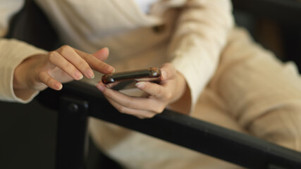 Fototapeta na wymiar Female hand using smartphone while relaxed sitting in workplace