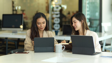 Two businesswomen working together with tablets on meeting table