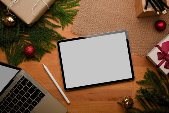 Top view of wooden table with tablet, laptop and decorations in Christmas concept
