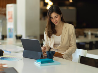 Businesswoman working with schedule book and tablet on worktable in cafeteria