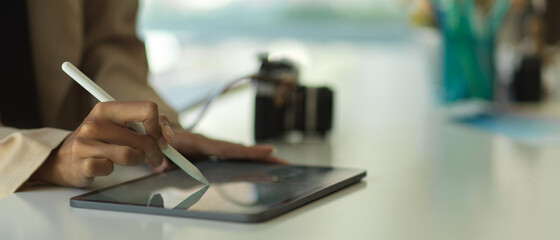 Businesswoman using tablet with stylus on office desk