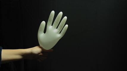Abstract background with hand holding medical glove in dark background