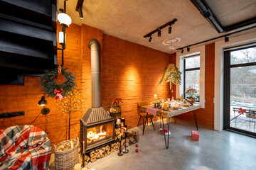 Beautiful loft-style interior with a fireplace and a dining table decorated for the New Year holidays