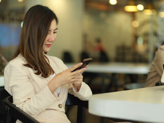 Businesswoman using smartphone while relaxing in office room