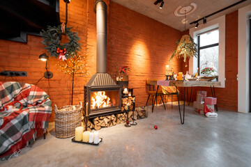 Fireplace area of a beautiful loft-style interior with real brick and concrete floors decorated for the New Year holidays. The concept of home comfort