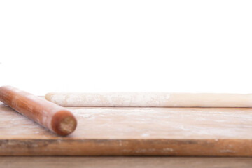 A piece of white flour and a rolling pin on a cutting board in front of a white background
