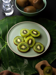 Fresh whole and sliced kiwi fruit on the table decorated with green leaf