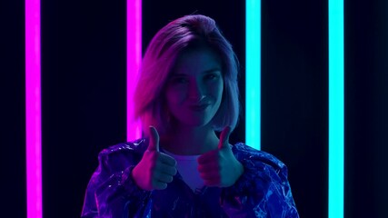 Portrait of a young stylish woman looking at the camera smiling and showing thumbs up gesture. Close up. Slow motion.