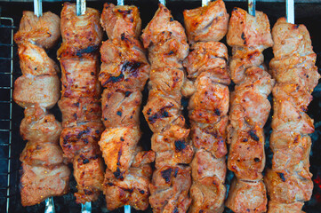 skewered pork kebab grilled over charcoal, smoke over a barbecue, medium cooking, close