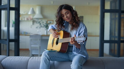 Girl playing guitar at home. Musician learning to play musical instrument