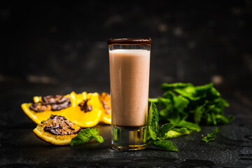 Alcohol cocktail in shot glass with chocolate liqueur, vodka, oranges and mint leaves. Selective focus. Shallow depth of field. 
