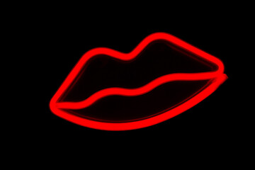 Blurry neon red lips close-up on a black isolated background.