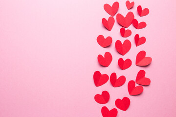 A lot of small hearts of red color against on a pink background. Happy Valentine's Day.
