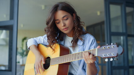 Girl practicing music on guitar. Female guitarist playing chords on guitar