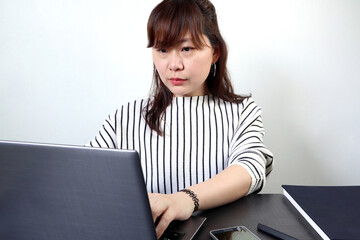 an asian business woman is working on a personal laptop computer on the working desk in office during making decision plan about business investment of her company in covid19 pandamic crisis