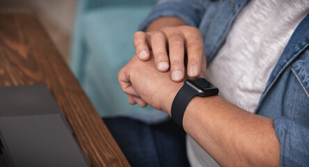 Naklejka premium Adult man monitors heart rate with smart watch on wrist