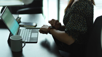 Female checking message on smartwatch while working in office room