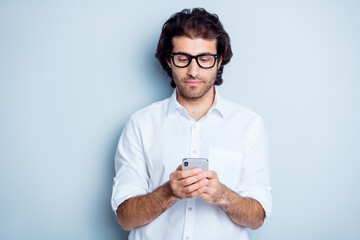Photo portrait of concentrated man typing holding phone in two hands isolated on clear white colored background