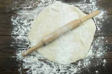 cooking fresh pizza. homemade pizza dough and rolling pin on a floured wooden table