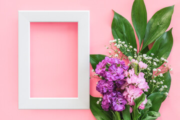White frame and bouquet flowers on pink purple background. Greeting card Flat Lay Mockup Concept Hello spring, Mother's day, Womens day, Good day Template for text and design