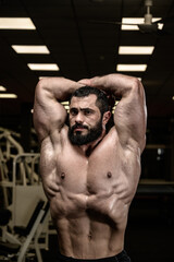Fototapeta na wymiar vacuum pose of strong young caucasian bearded man fitness bodybuilder athlete in sport gym
