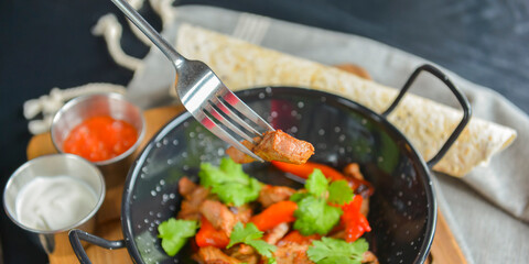 Vegetables and meat in wok pan served with lavash bread and different kinds of sauce. Close up.