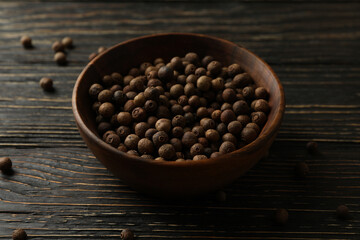 Bowl with peppercorns on wooden table, close up