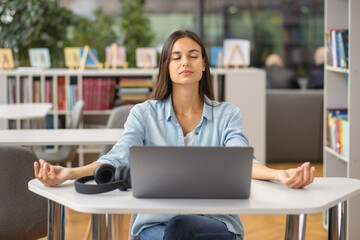 Beautiful happy young woman or student female meditates at the workplace