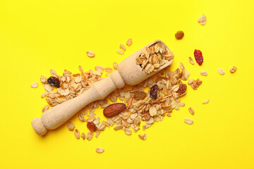 Wooden scoop and granola on yellow background