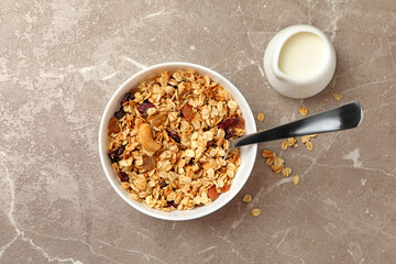 Bowl with granola and milk on gray background