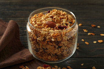 Glass jar with tasty granola on wooden background