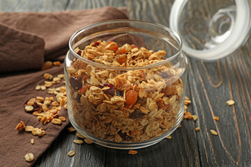 Glass jar with tasty granola on wooden background