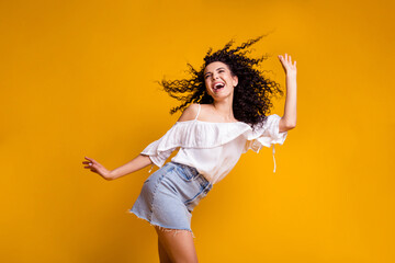 Fototapeta na wymiar Profile photo of young cheerful funny curly brunette woman dancing wearing white top blue skirt isolated on vivid yellow colored background