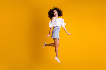 Fototapeta na wymiar Photo of young crazy girl jump girlish hands excited wear white blouse denim mini skirt sneakers isolated yellow color background
