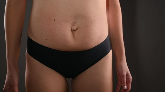Close-up of a woman jumping and her fat belly shaking. Female flabby belly after childbirth, diastasis, stretch marks.