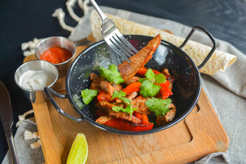 Vegetables and meat in wok pan served with lavash bread and different kinds of sauce. Close up.